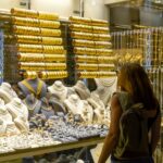 Kvinna som tittar in genom skyltfönster på guldsmycken