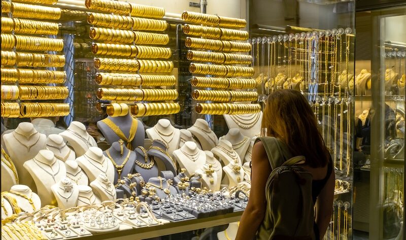 Kvinna som tittar in genom skyltfönster på guldsmycken
