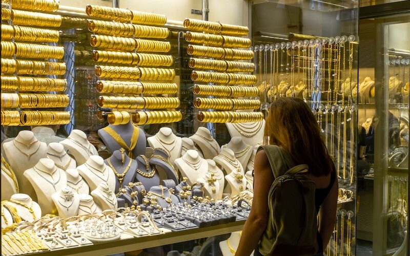 Kvinna som tittar in genom skyltfönster på guldsmycken